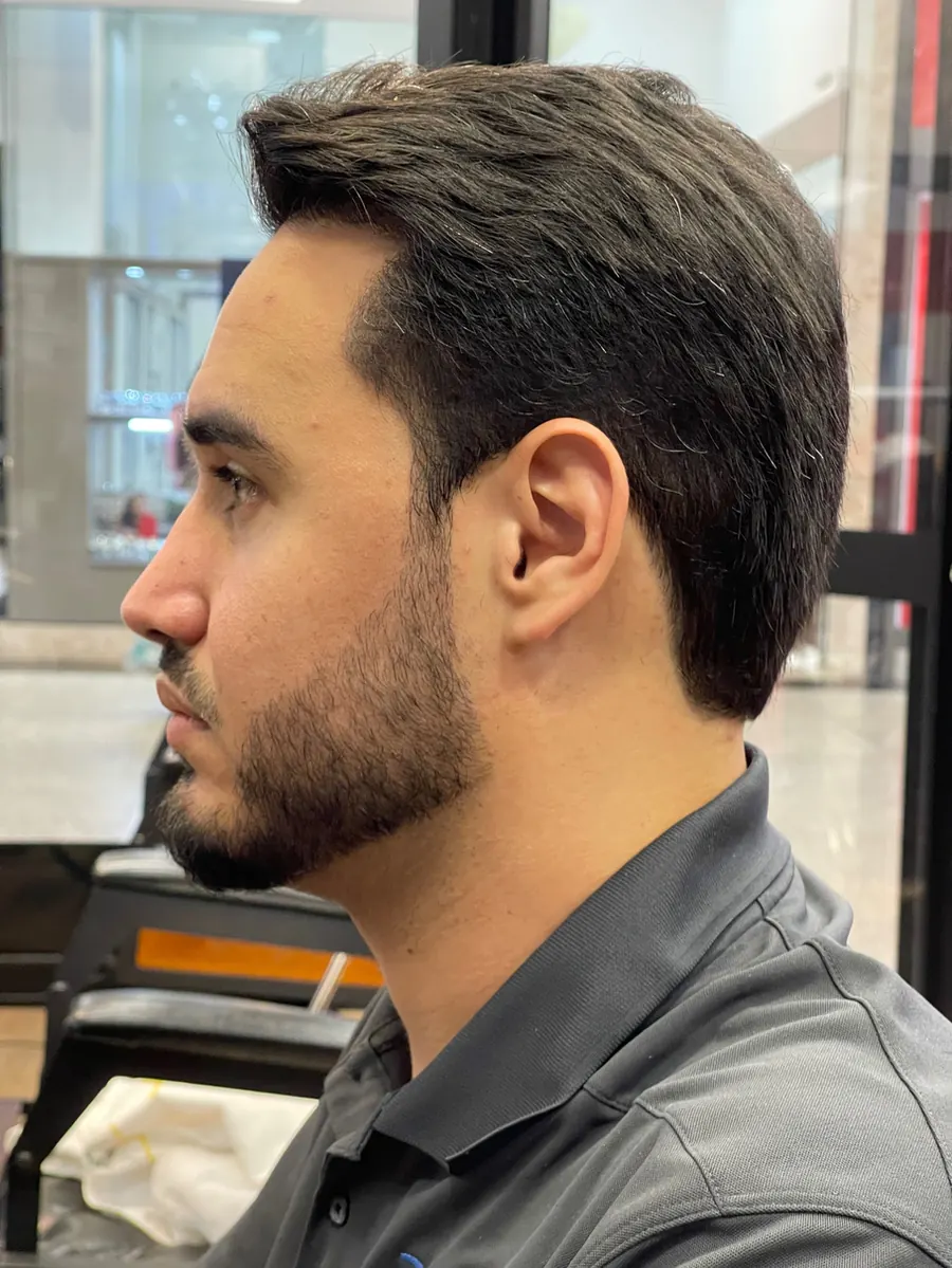 O mesmo cliente de perfil depois, com o cabelo penteado para trás e a barba alinhada